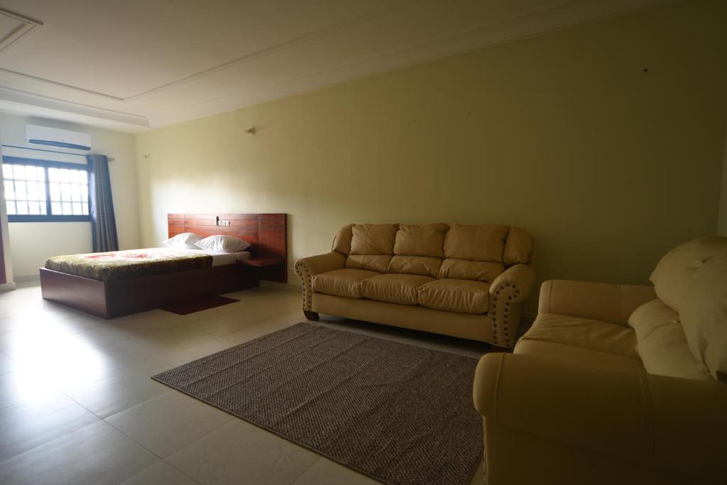 a living room with a couch and a bed at Hotel Mirambeau in Lomé