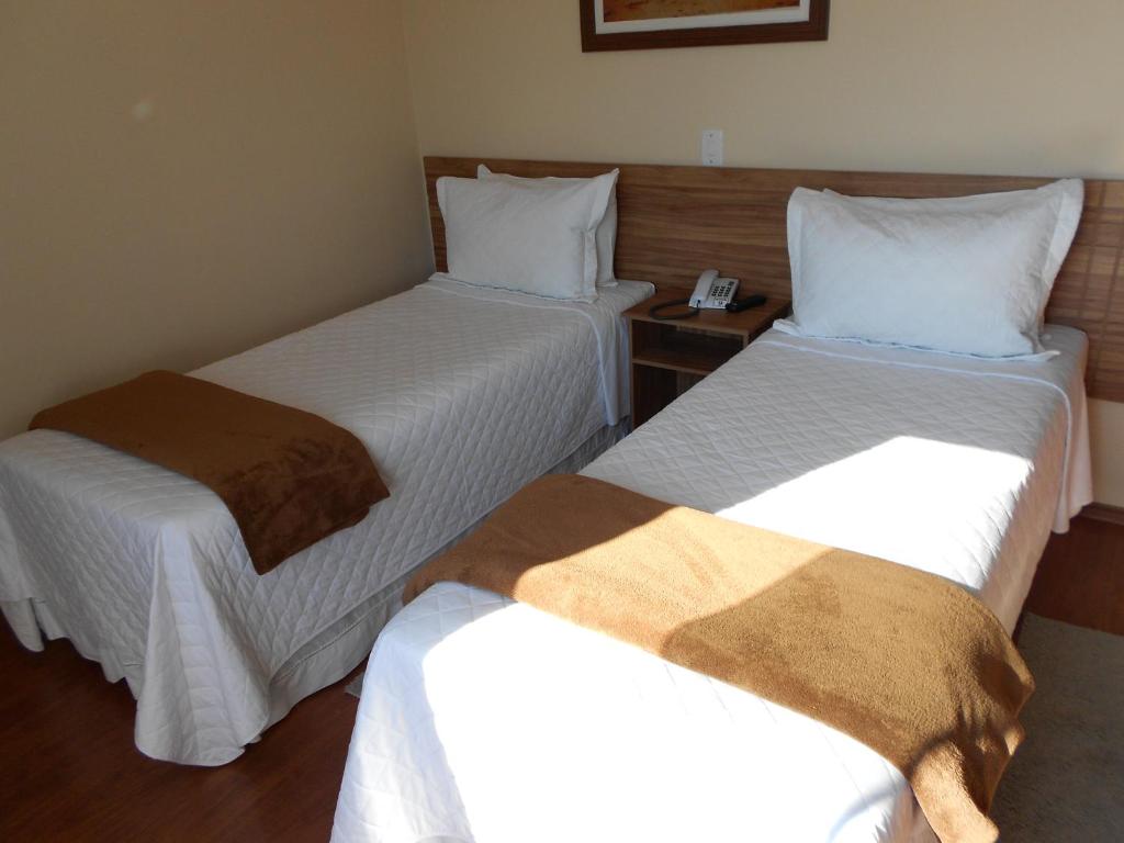 a hotel room with two beds with white sheets at Hotel JWF in Piedade