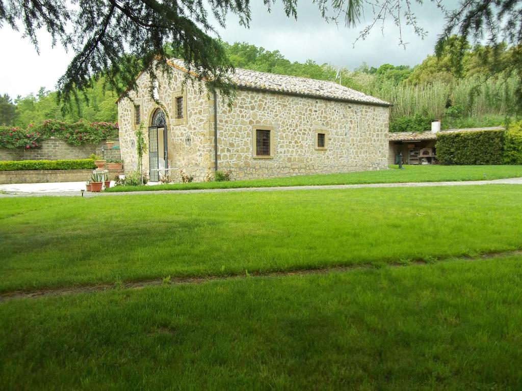 a stone building with a grass field in front of it at Il Mulino in Maremma in Farnese