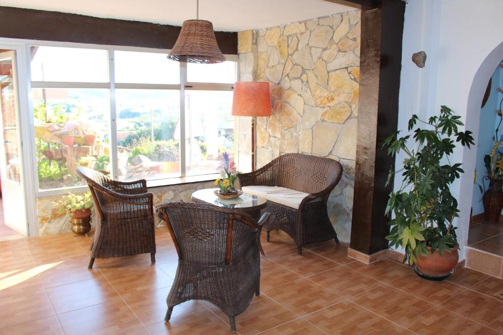 a living room with chairs and a table and a stone wall at Posada la Maza in Arnuero