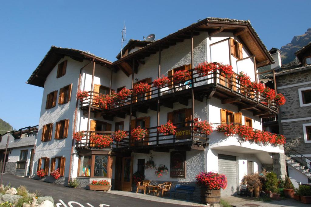 un edificio blanco con flores rojas en los balcones en Residence Pavou, en Cogne