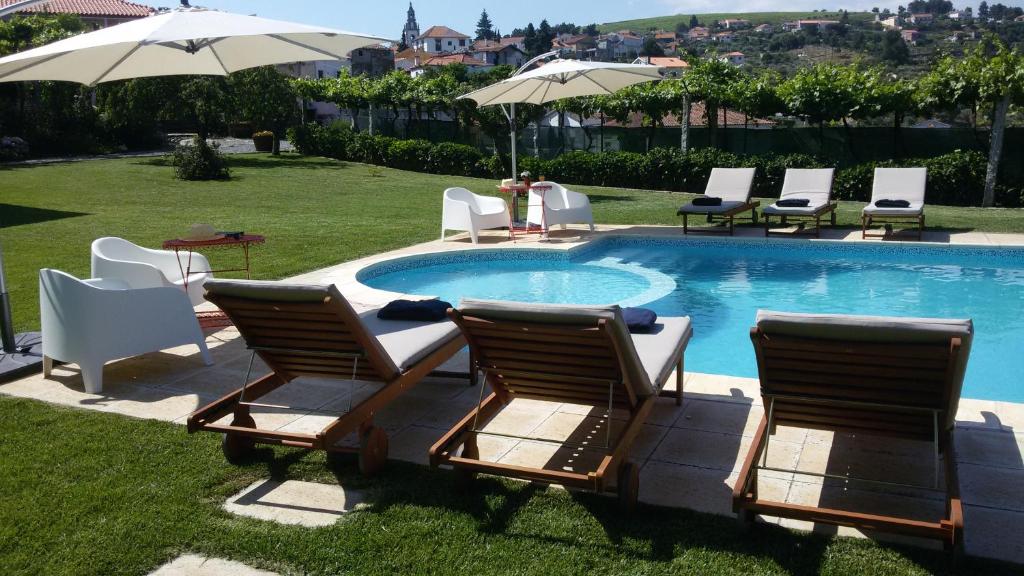 een groep stoelen en parasols naast een zwembad bij Casa Castedo do Douro in Castedo