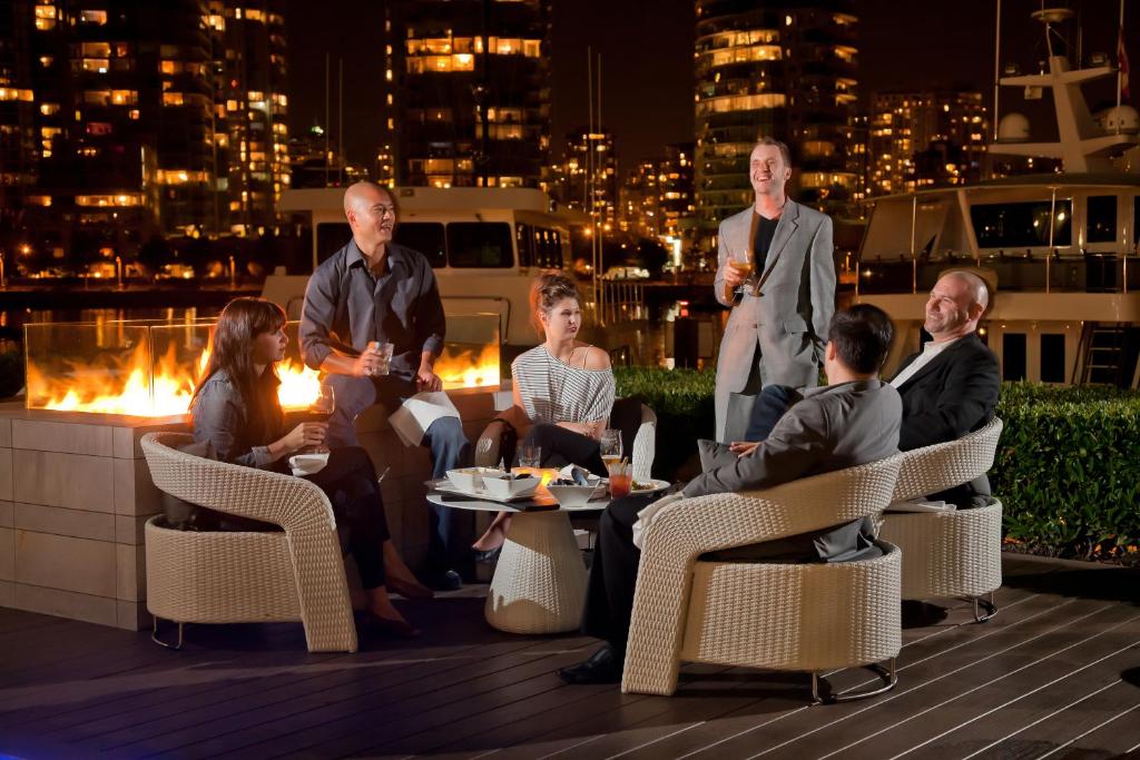 a group of people sitting on a rooftop at night at Granville Island Hotel in Vancouver