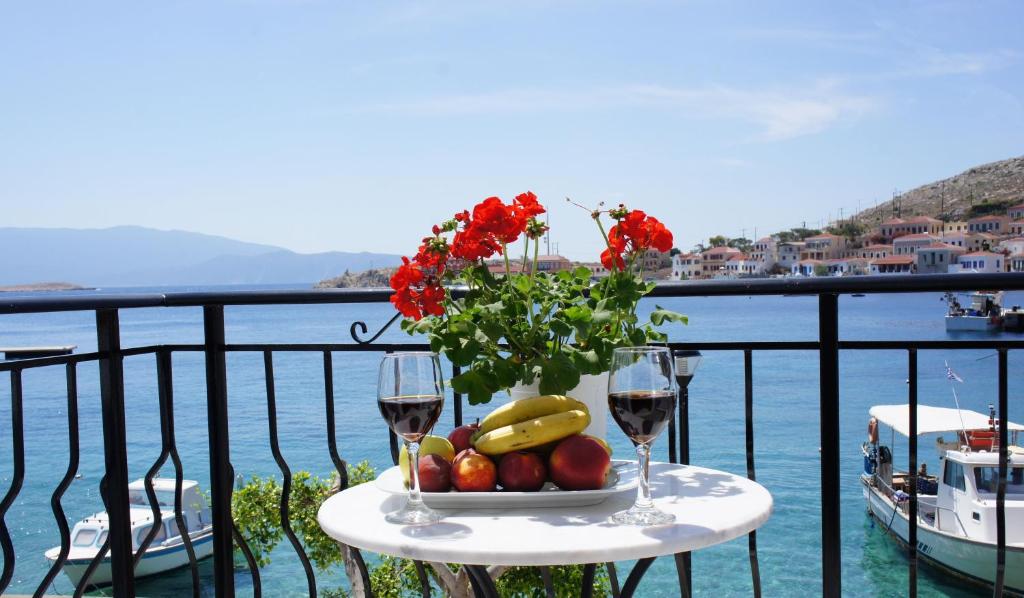 a table with a bowl of fruit and two glasses of wine at Aegean View Villas in Halki