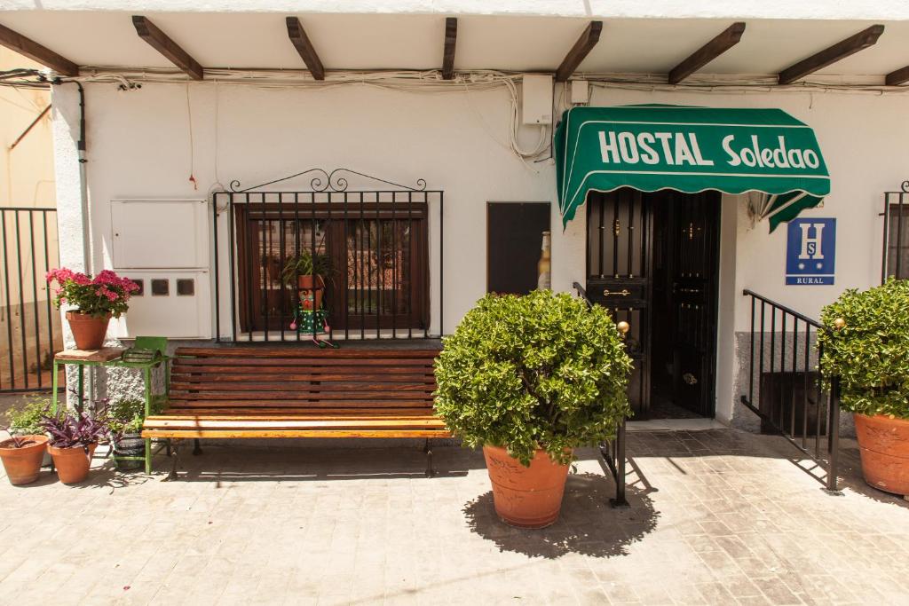 a wooden bench in front of a building at Hostal Soledao in Los Baños