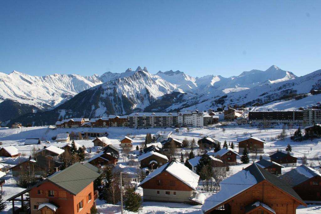 a town covered in snow with mountains in the background at Le Mont Charvin in La Toussuire