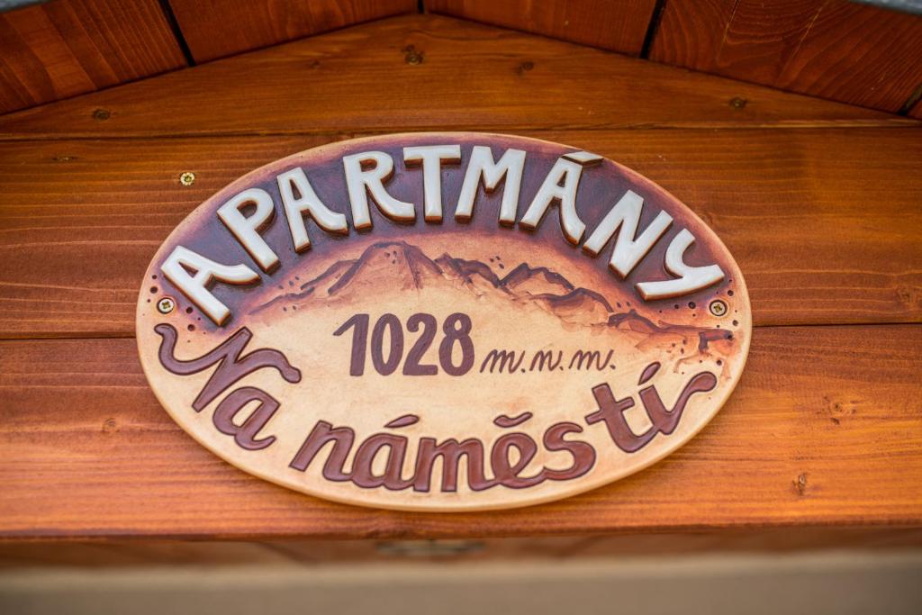a sign on a wooden wall with a mountain sign at Apartmány Na náměstí in Boží Dar