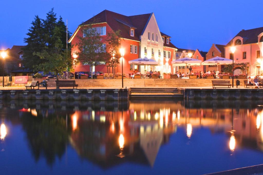 a group of buildings next to a river at night at Der Insulaner - Hotel & Restaurant in Malchow