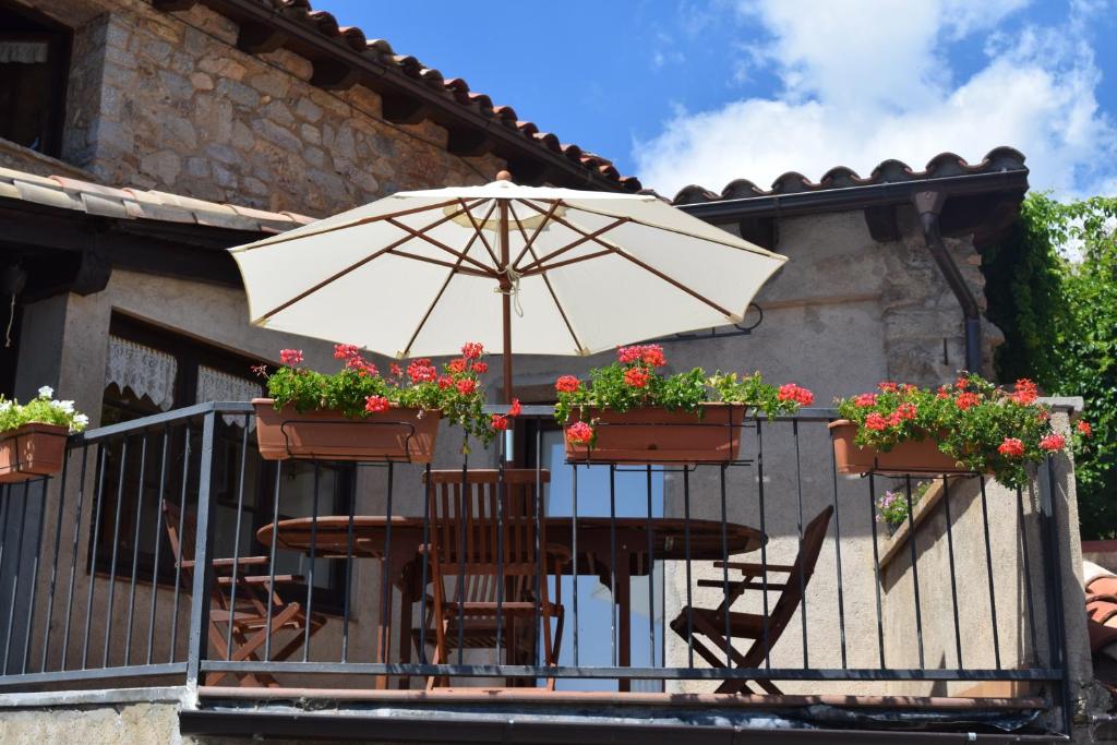 un tavolo e sedie con ombrellone su un balcone di Cal Genetó a Castellar de NʼHug
