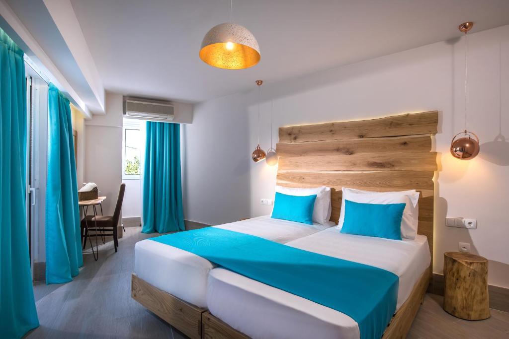 um quarto com uma cama grande com lençóis azuis e cortinas azuis em Senses Blue Boutique hotel em Hersonissos