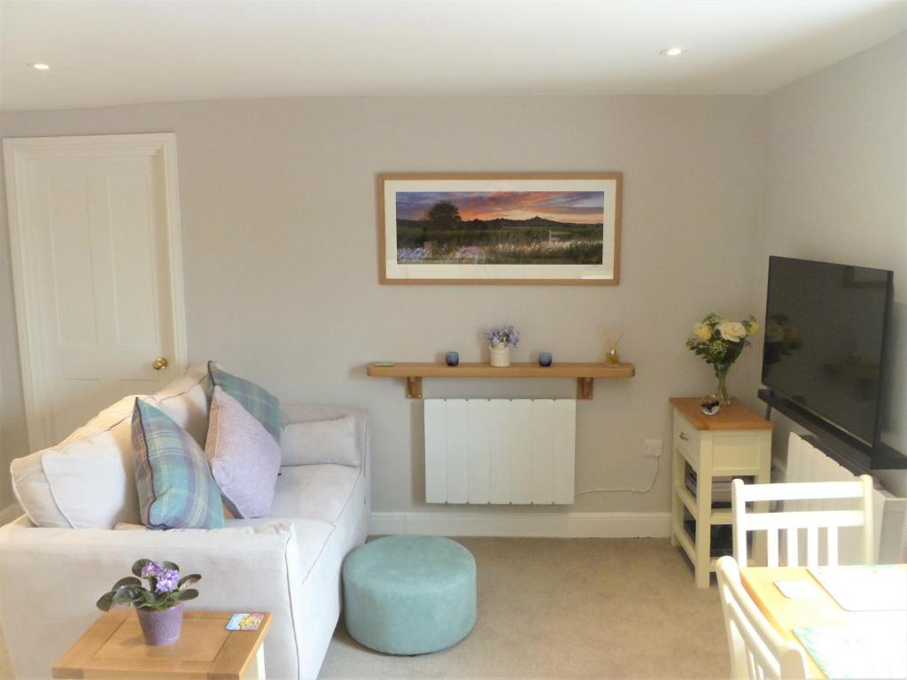 a living room with a white couch and a tv at Chalice Loft in Glastonbury