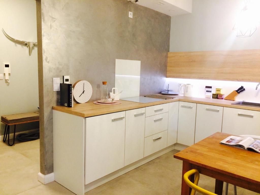 a kitchen with white cabinets and a wooden table at Piper Cytadela Apartament in Poznań