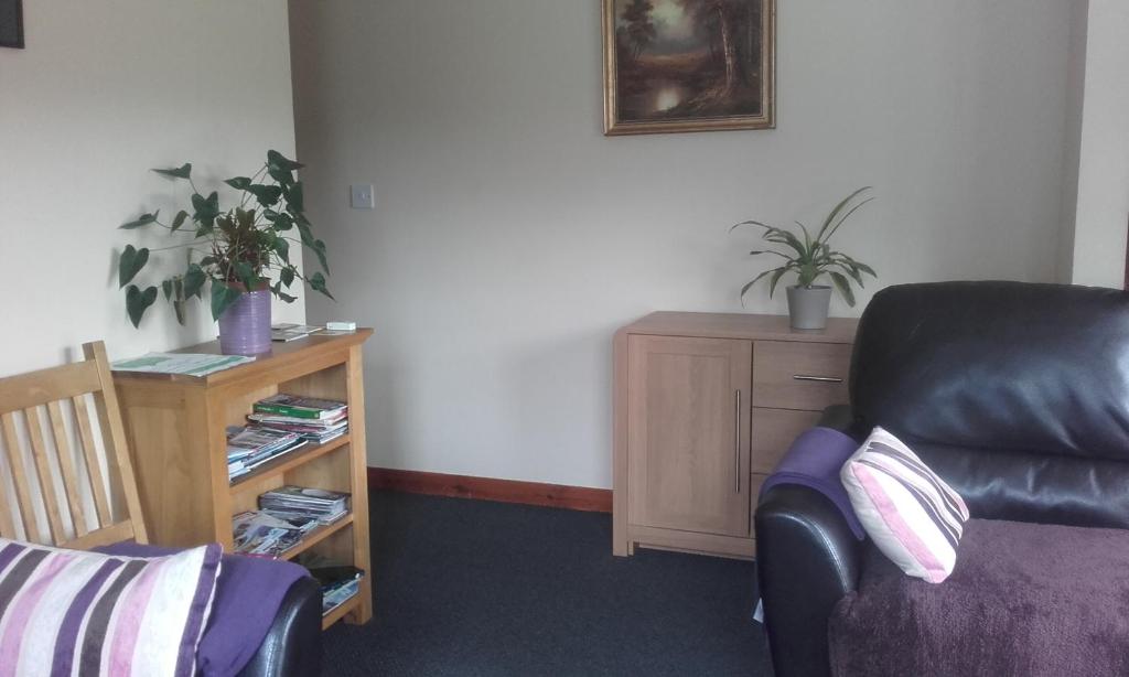 a living room with a black leather chair and a table at Rockfoot B&B in Fintry