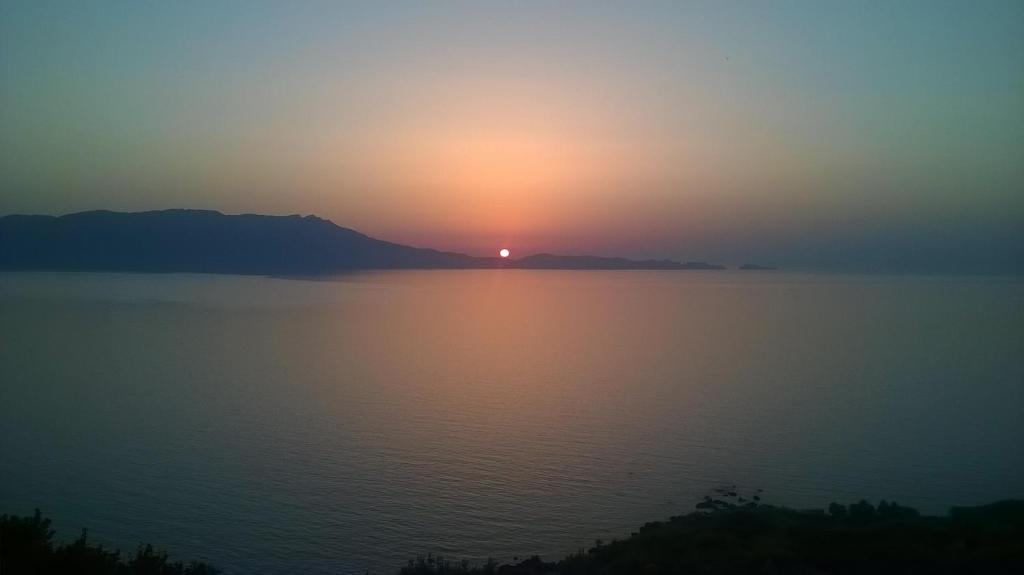 a sunset over a large body of water at Michalis Holiday Home in Ravdhoúkha