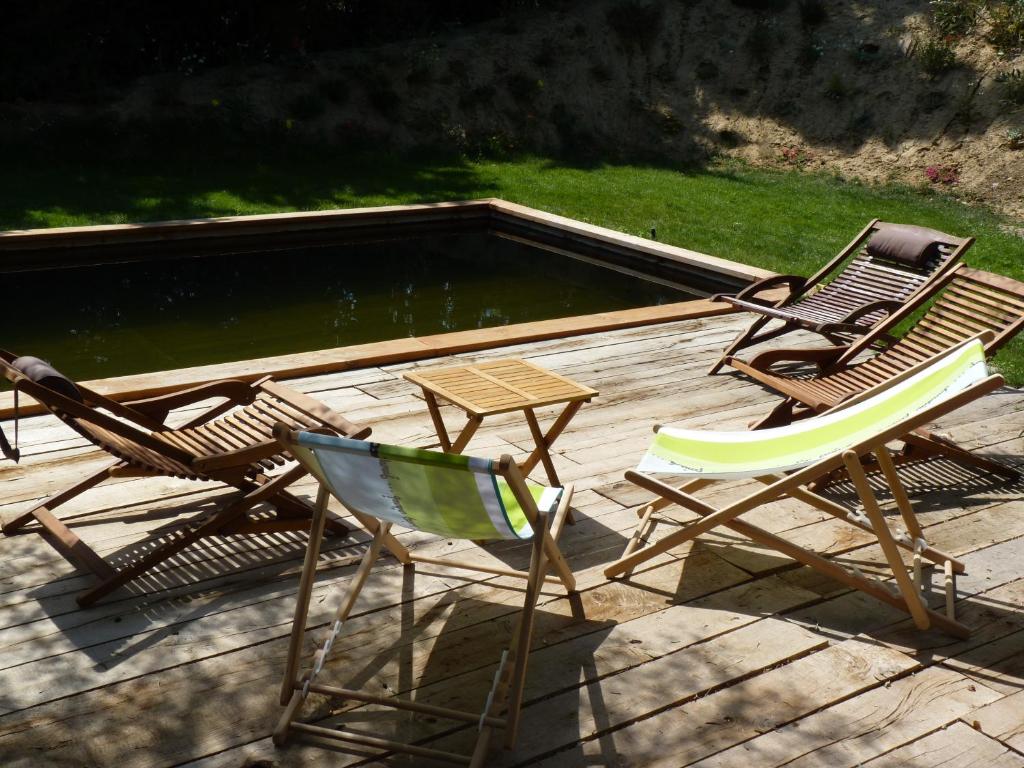 3 chaises et une table sur une terrasse avec un étang dans l'établissement Mas Bonement, à Arles