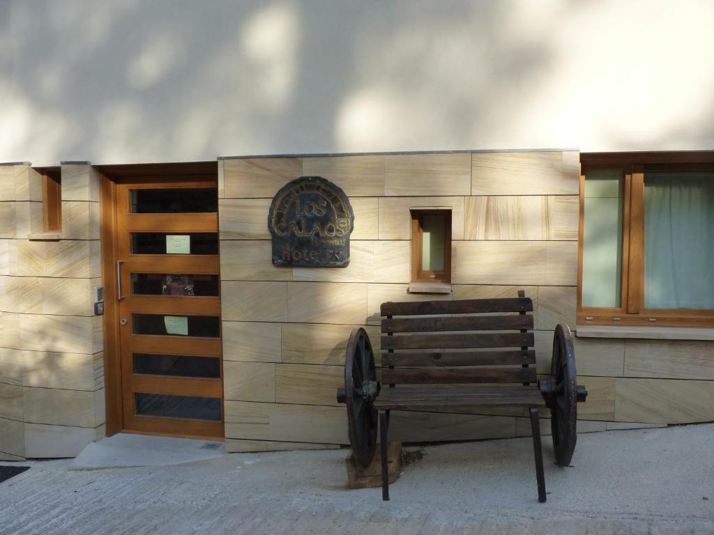 un banco de madera frente a un edificio con un cartel en Los Calaos de Briones, en Briones