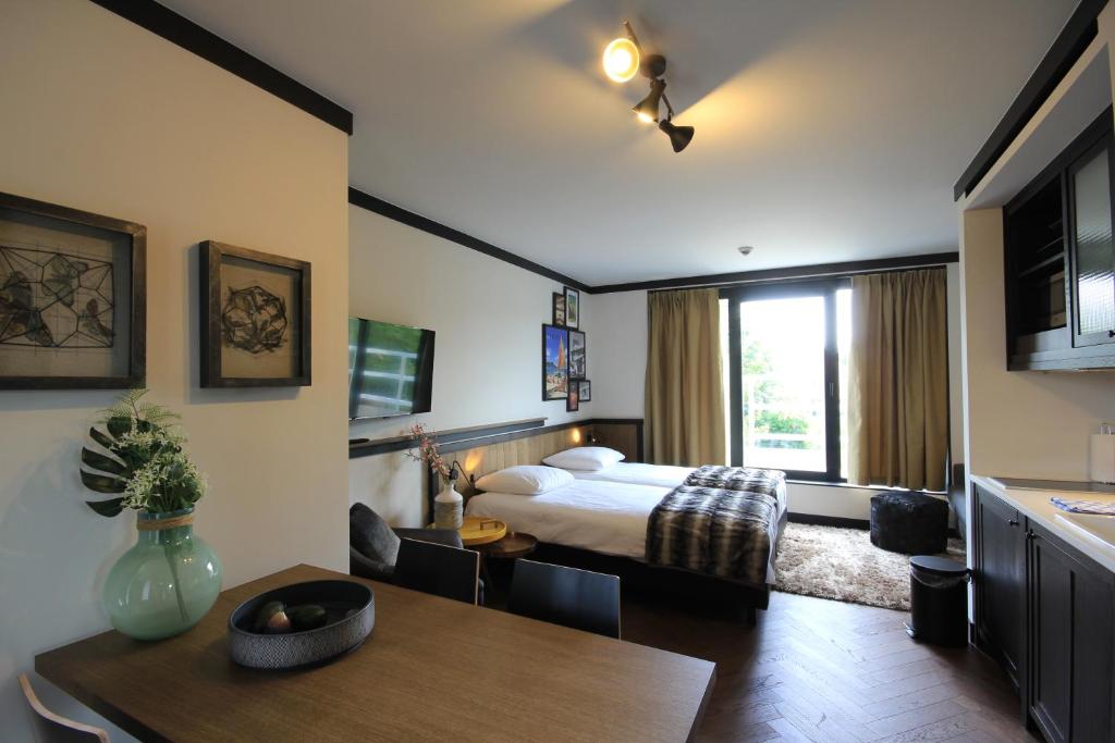 a bedroom with a bed and a table and a dining room at Getaway Studios Brussels Airport in Zaventem