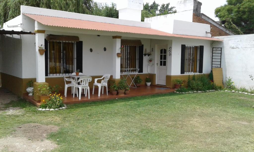 Casa con porche con mesa y sillas en La Colonial Cabañas en Villa Cura Brochero