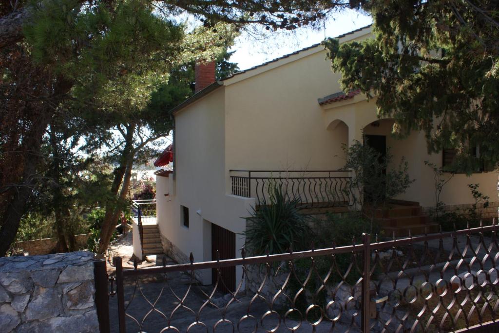 a white building with a fence in front of it at Villa Punta in Okrug Donji