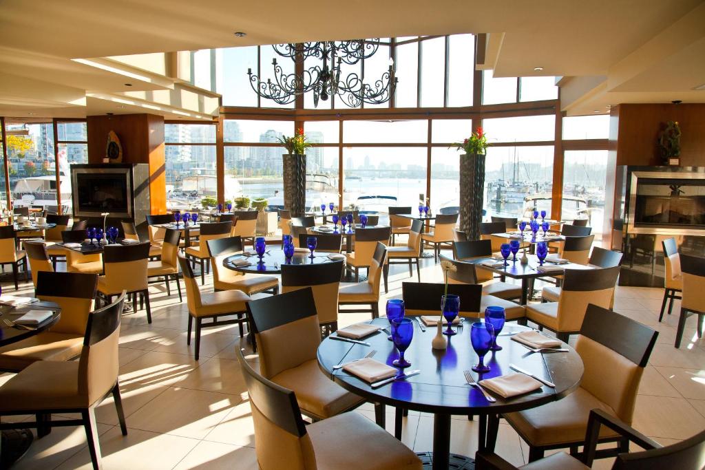 a restaurant with tables and chairs and a large window at Granville Island Hotel in Vancouver