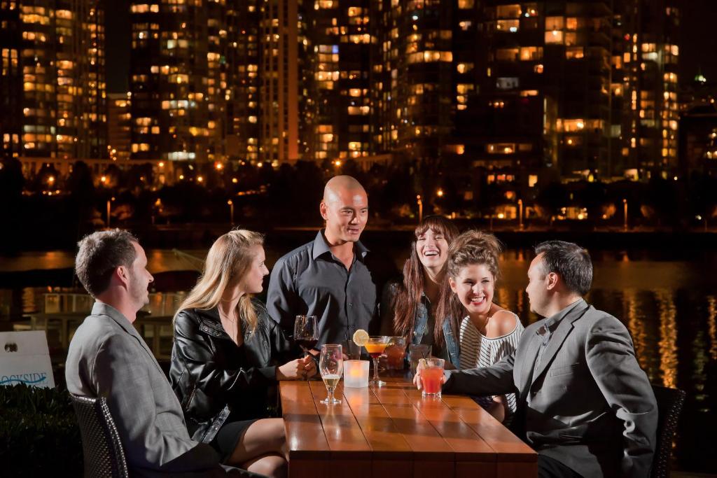 a group of people sitting around a table with drinks at Granville Island Hotel in Vancouver