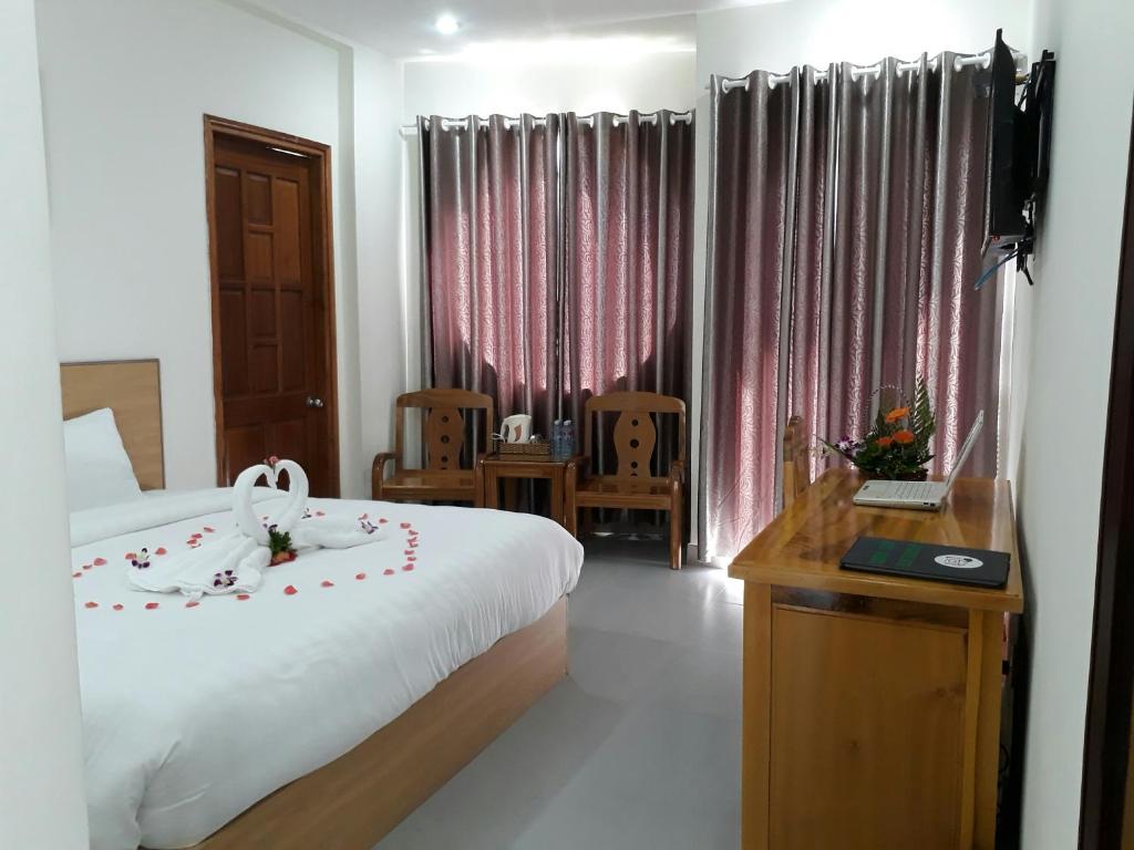 Habitación de hotel con cama, escritorio y TV. en Paradise Hotel, en Hoi An