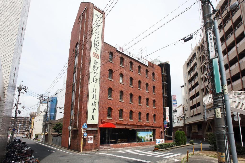 ein rotes Backsteingebäude in einer Stadtstraße in der Unterkunft Kurashiki Global Hotel in Kurashiki