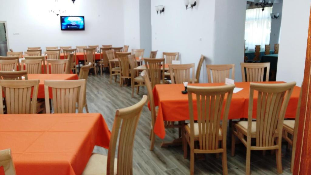 un comedor con mesas y sillas de naranja en Hostel Teleki en Sovata