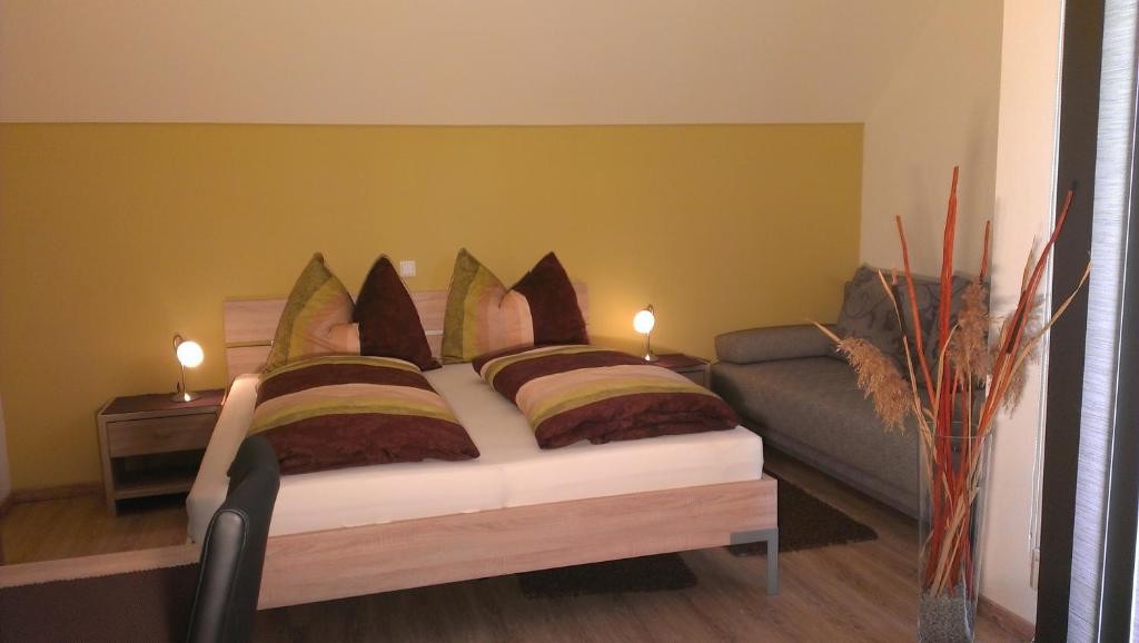 een slaapkamer met een bed met kussens en een bank bij Weingut Wagner in Leodagger
