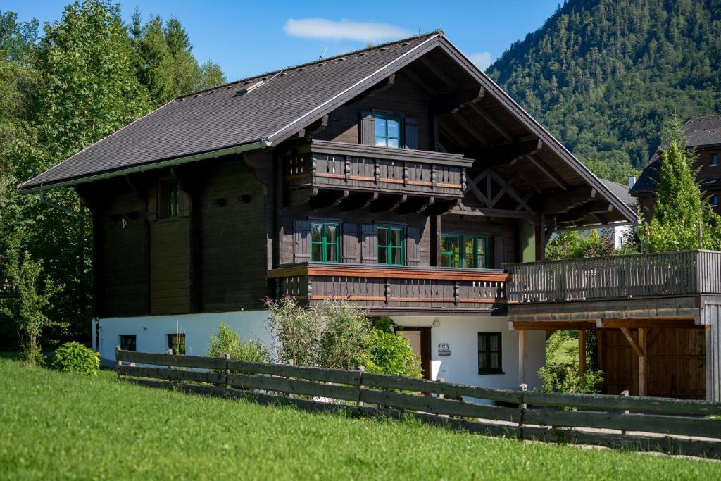 uma grande casa de madeira com uma varanda numa colina em Ausseer Chalet (nahe Hallstatt), Ferienhaus em Bad Aussee