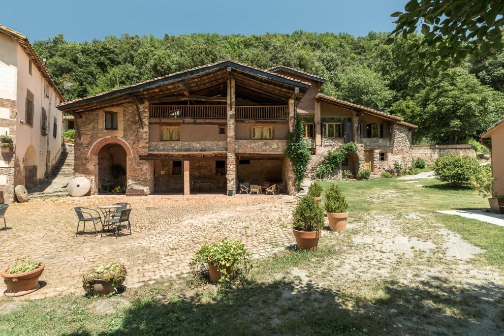 Una gran casa de piedra con un patio enfrente. en Can Solà La Vall de Bianya, en Sant Pere Despuig
