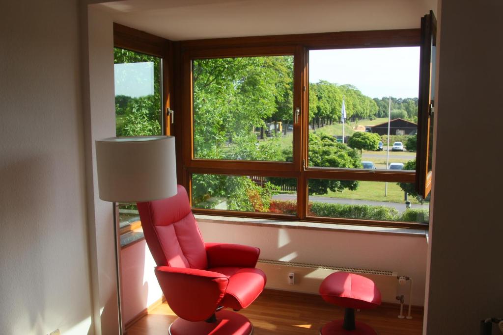 Habitación con silla roja y ventana en Wohnen auf Zeit am Golfplatz Motzen, en Motzen