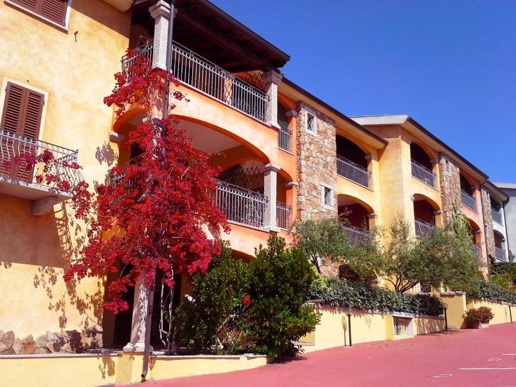 un edificio con un árbol rojo delante de él en Borgo Bellavista Badesi, en Badesi