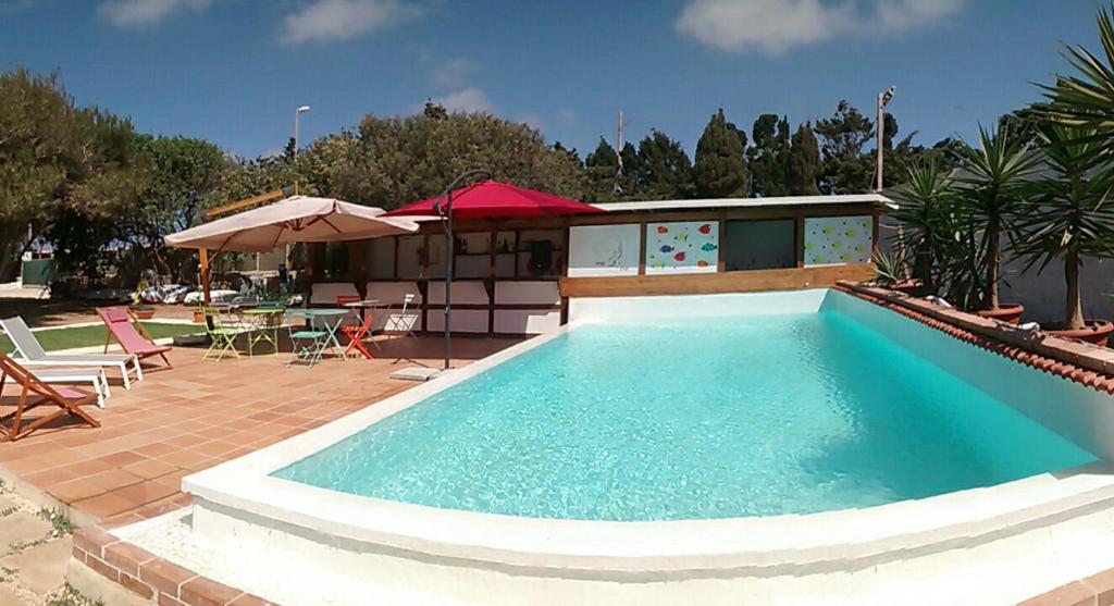 a large swimming pool with chairs and an umbrella at bolinajazz in Lampedusa