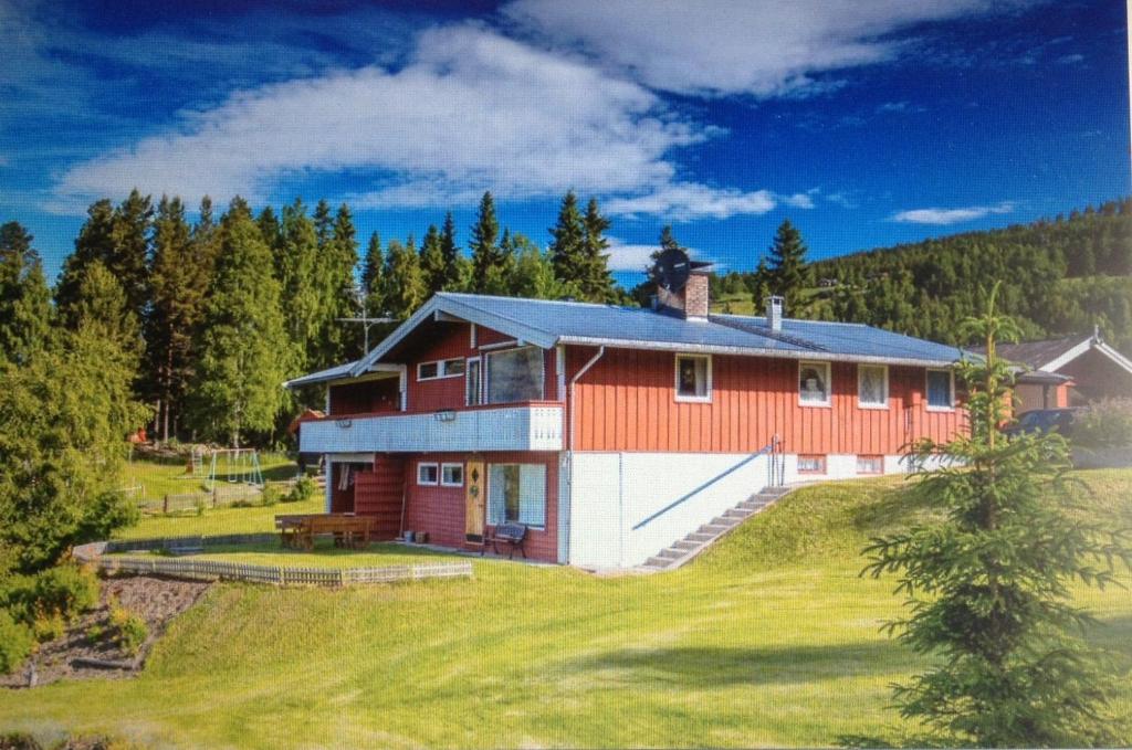 ein rotes und weißes Haus auf einem Hügel mit Bäumen in der Unterkunft Åsgardane Gjestegard in Gol
