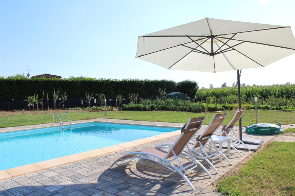 un grupo de sillas y una sombrilla junto a una piscina en Agriturismo Villa Gaia, en Lonato