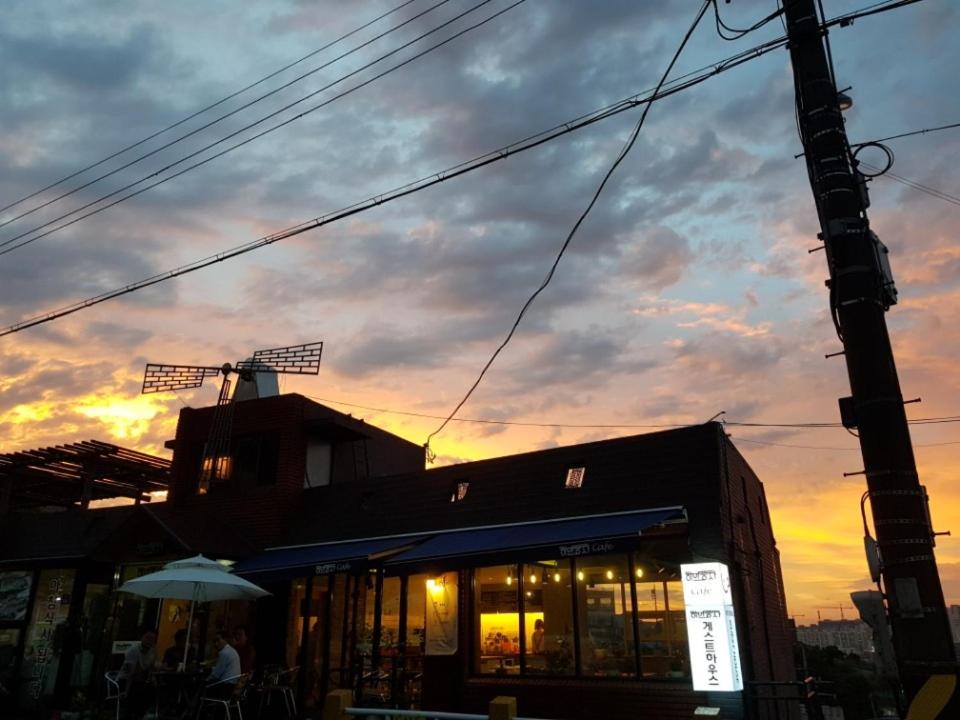 un edificio con sombrilla frente a la puesta de sol en White Windmill Guesthouse, en Mokpo