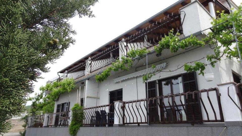 a white building with balconies and plants on it at Delfin Apartments in Sveti Juraj