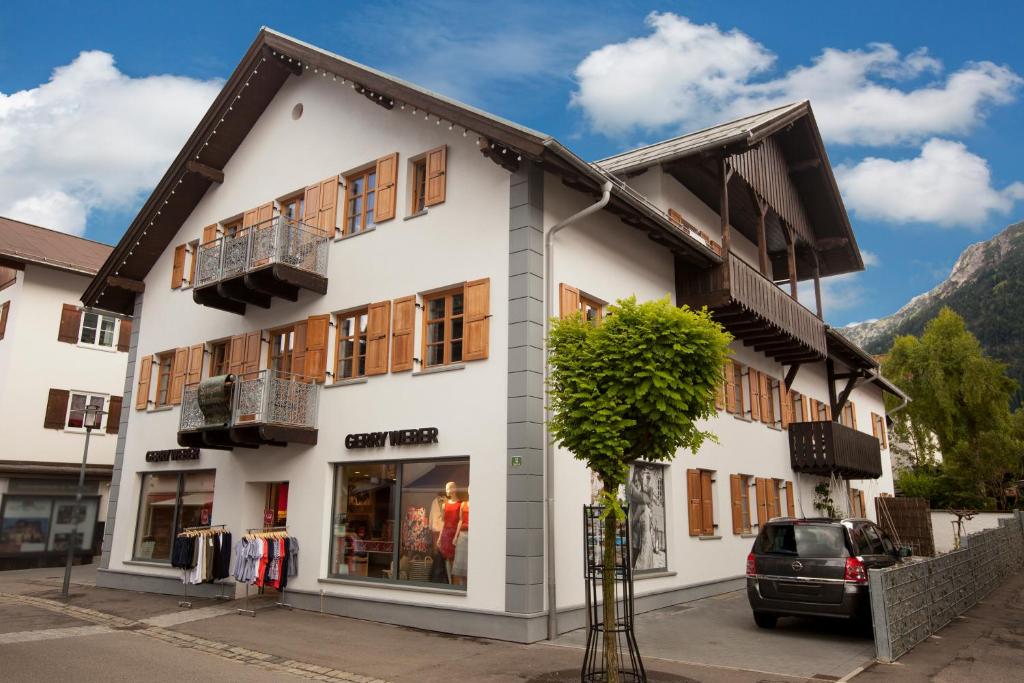 un bâtiment blanc avec un arbre devant lui dans l'établissement Georg Mayer Haus, à Oberstdorf