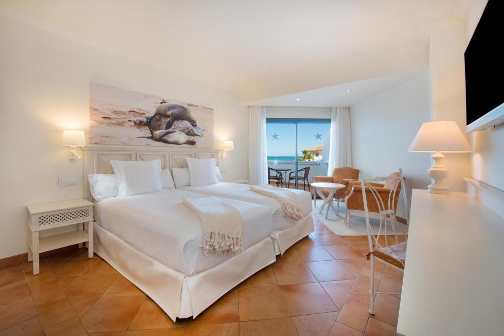 a bedroom with a large white bed with a view of the ocean at Iberostar Selection Andalucia Playa in Chiclana de la Frontera