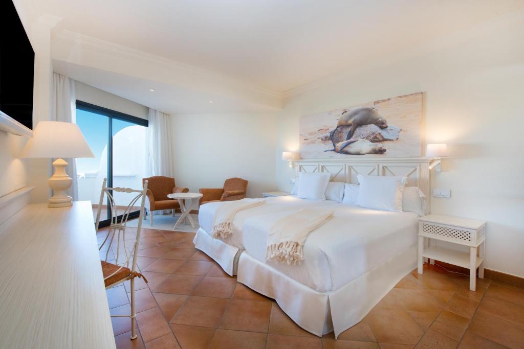 a bedroom with a large white bed with a painting on the wall at Iberostar Selection Andalucia Playa in Chiclana de la Frontera