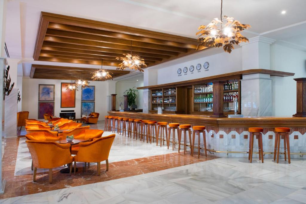 a restaurant with a bar with orange chairs at Iberostar Selection Andalucia Playa in Chiclana de la Frontera