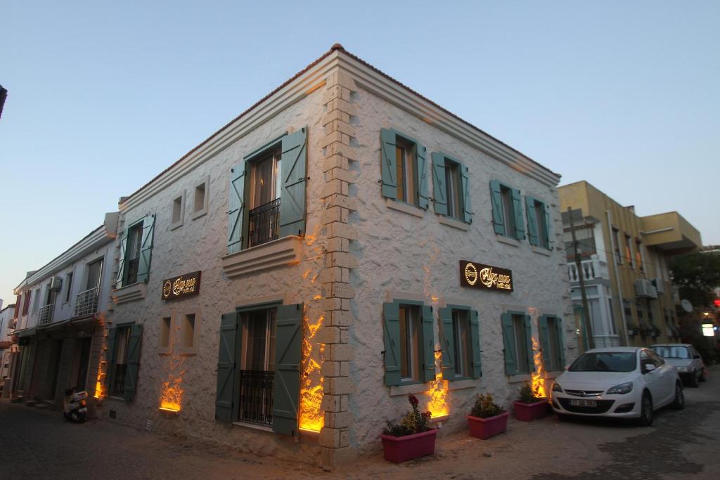 Alya Mou Butik Hotel في تشيشمي: مبنى على شارع فيه سيارة تقف امامه