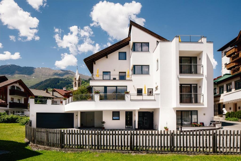 a white house with a fence in front of it at Appart's Platzl in Serfaus