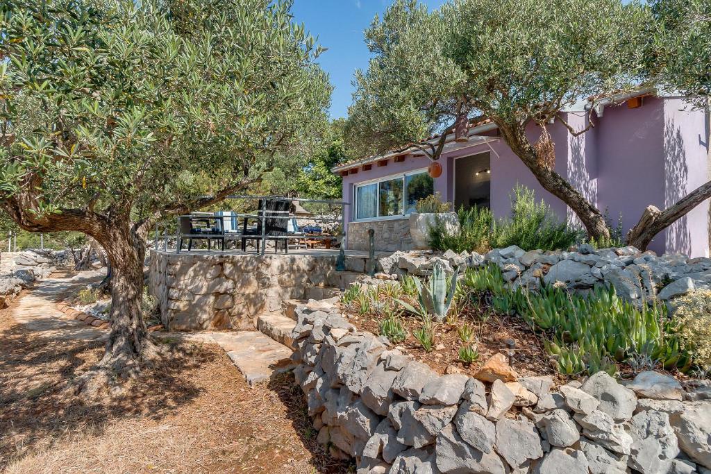 uma casa com uma parede de pedra e árvores em Holiday home Nikol em Veli Lošinj