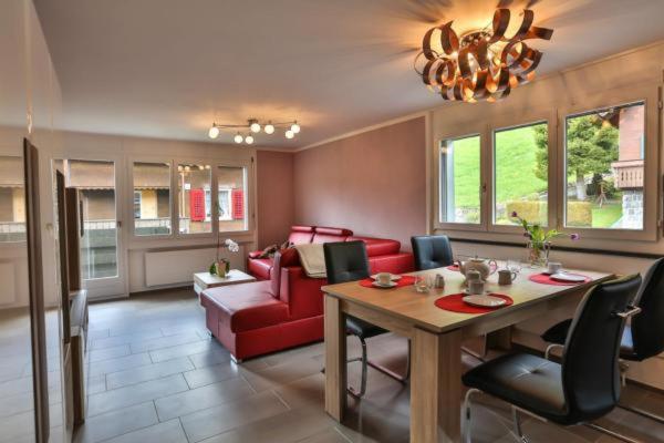 sala de estar con mesa y sofá rojo en Wildhaus Weiherhof en Wildhaus