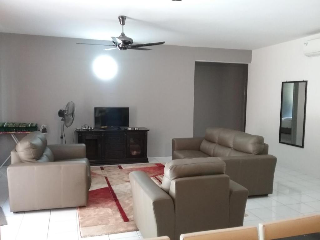 a living room with two couches and a ceiling fan at Anjung Homestay in Sepang