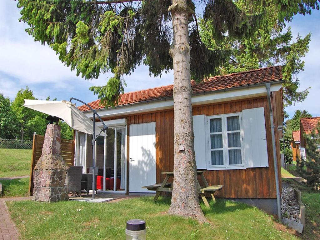 une petite maison avec un arbre dans la cour dans l'établissement Ferienanlage Bansin Seepferdchen 4, à Bansin