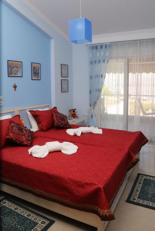 sypialnia z dużym czerwonym łóżkiem i ręcznikami na nim w obiekcie Athina Luxury Apartment w mieście Keramotí