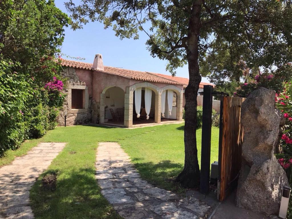 Abbiadori的住宿－Villa La Quercia - Capriccioli，享有带庭院的房屋外部景致